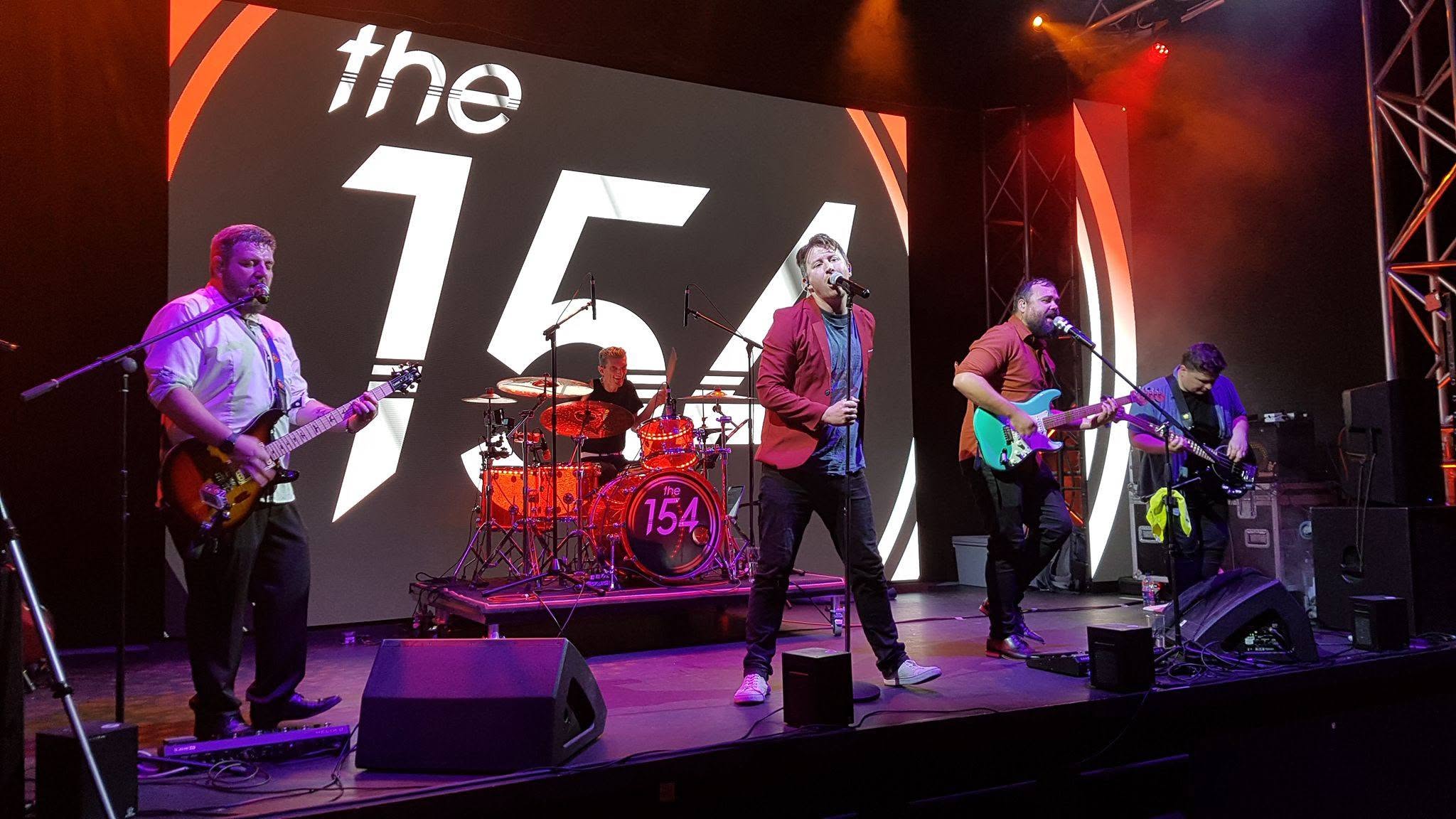 The 154 on stage in front of their branded LED screen